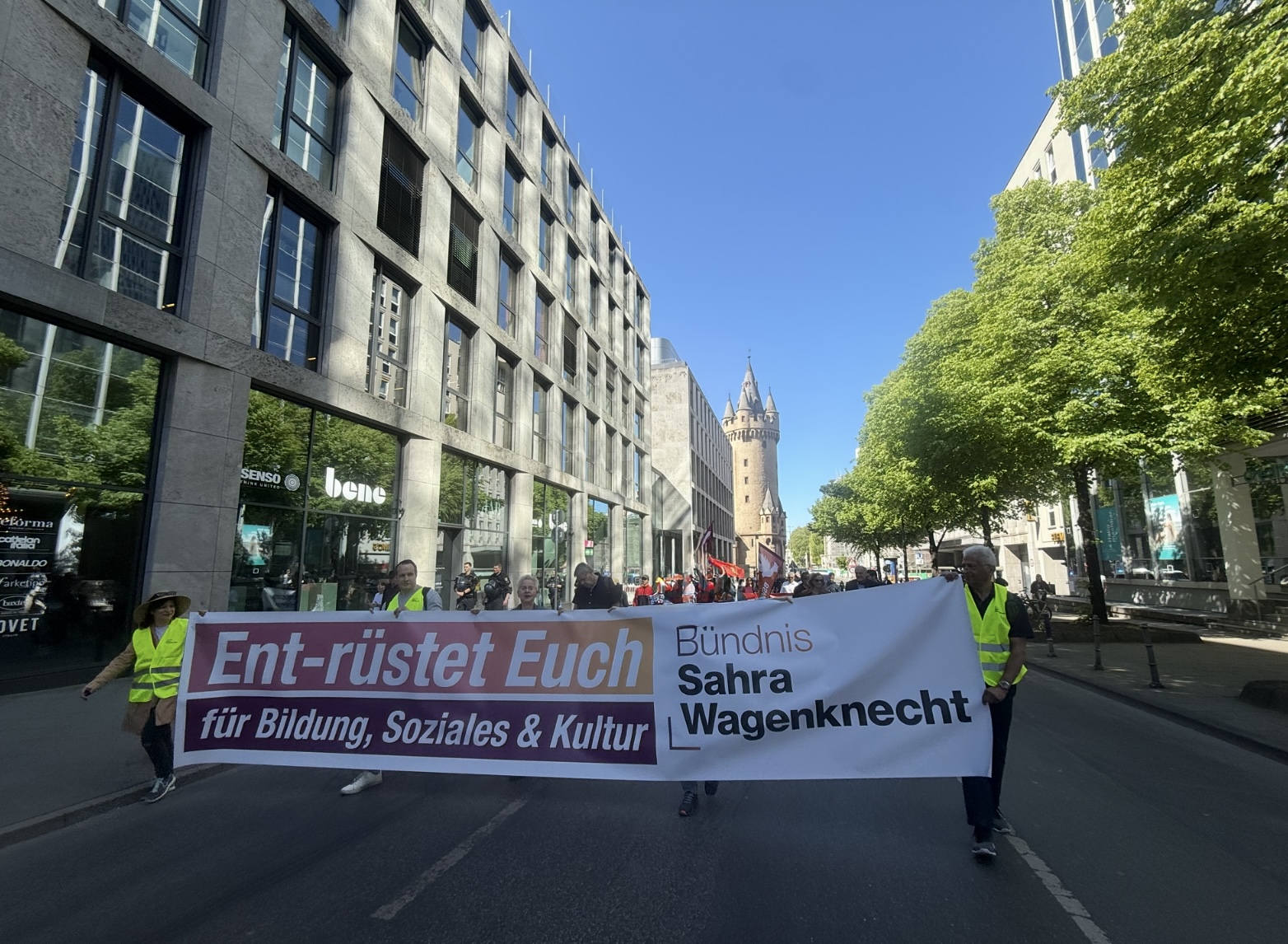 Mitglieder des BSW tragen zum ersten Mai ein langes Transpi auf dem steht "Ent-rüstet Euch"